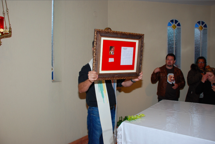 Padre George Rodrigues segurando o quadro que contém a Relíquia