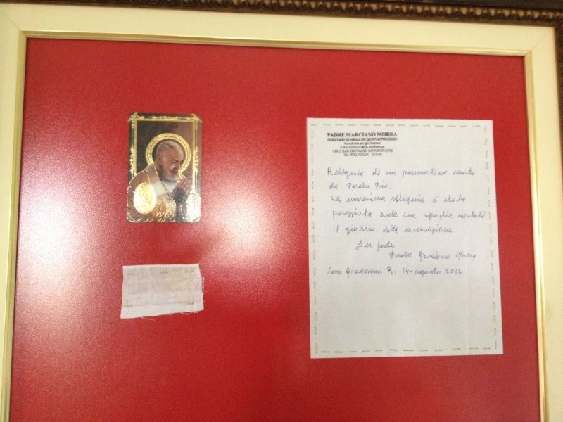 À esquerda acima a imagem de Padre Pio, logo abaixo a Relíquia de primeiro grau, e à direita uma carta do Padre Marciano Morra